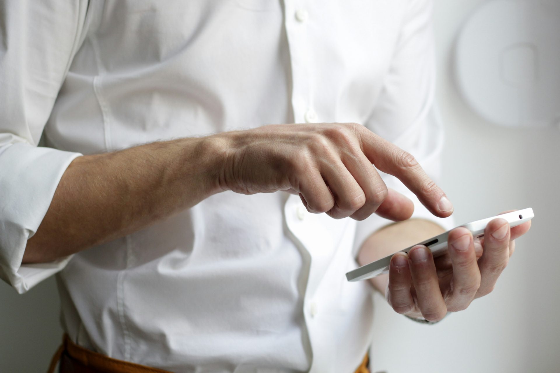 Person in einem weißen Hemd, die ein weißes Android-Smartphone hält.